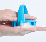 Shampoobürste mit Handschlaufe und Schaum – Anwendung am baugleichen blauen Modell; geliefert wird Grau